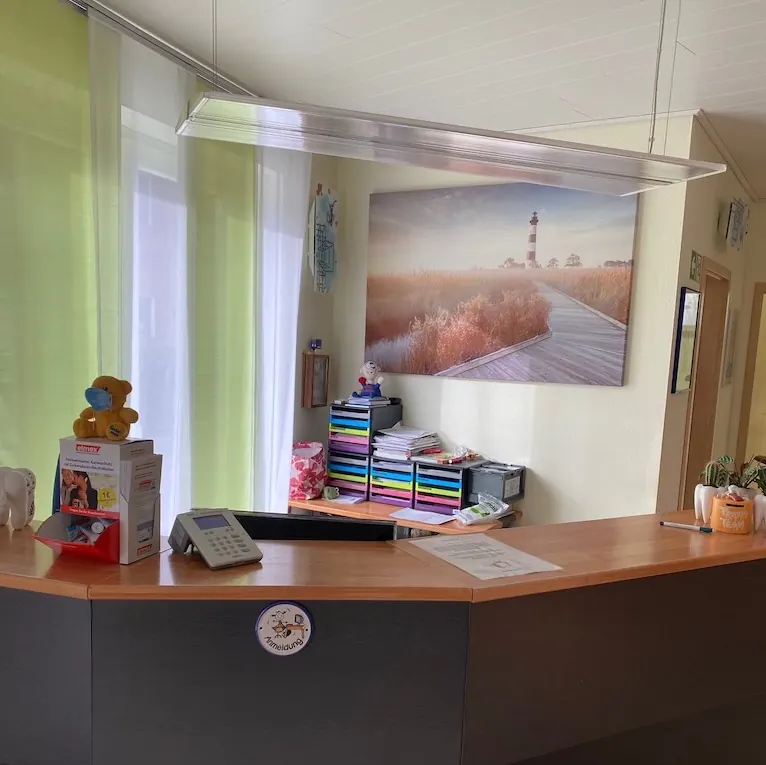 Empfangstresen der Praxis mit einem Bild von einem Leuchtturm an der Wand